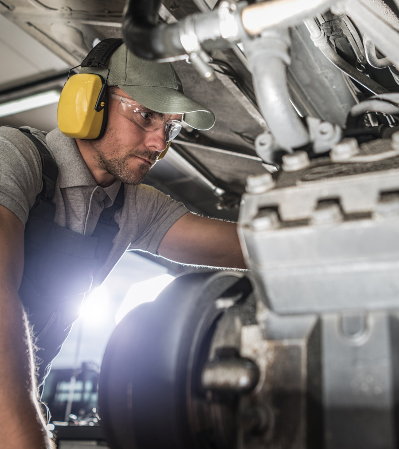 Ein Industriemechaniker, der Kopfhoerer traegt und einer Maschine konzentriert arbeitet.