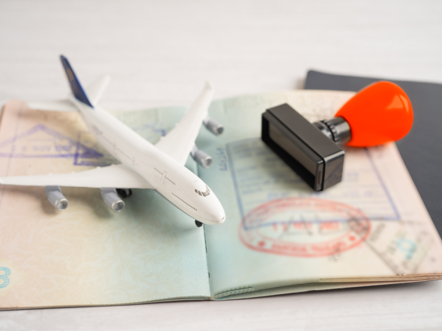 Ein Pass mit einem Stempel sowie ein Modellflugzeug liegen auf einem Schreibtisch.