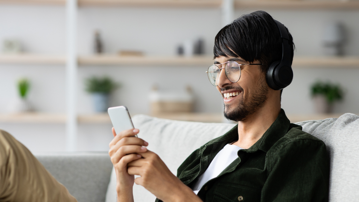 Ein junger Mann haelt laechelnd ein Smartphone in der Hand